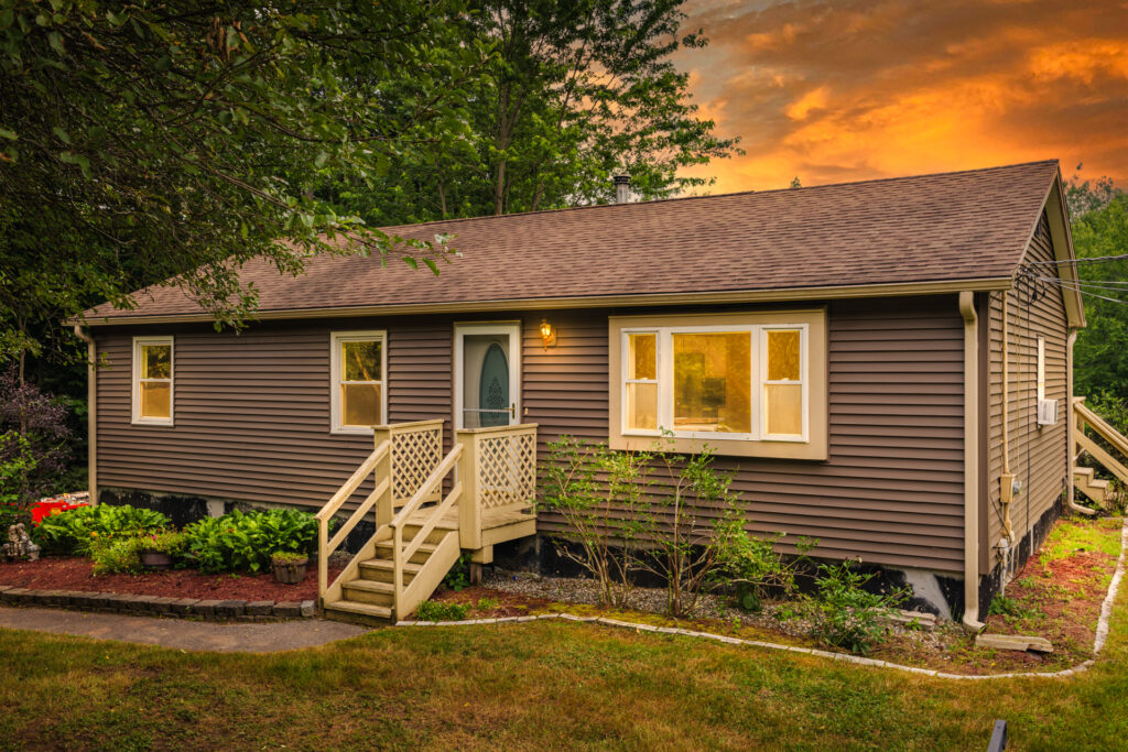 Dramatic twilight exterior image of the front of a cottage style home. This is an after image edited for virtual twilight.